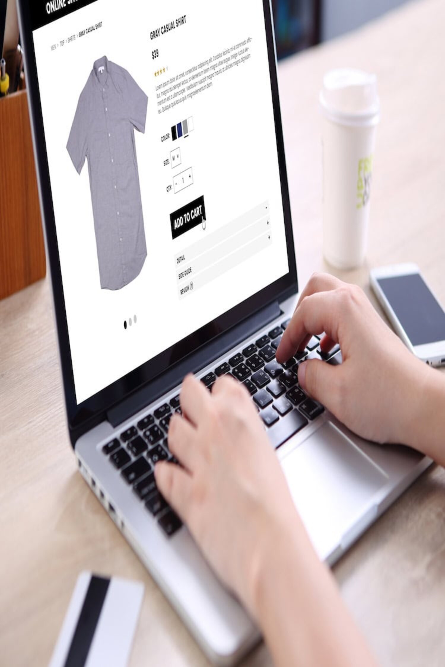 People buying casual shirt on ecommerce website with smart phone, credit card and coffee on wooden desk