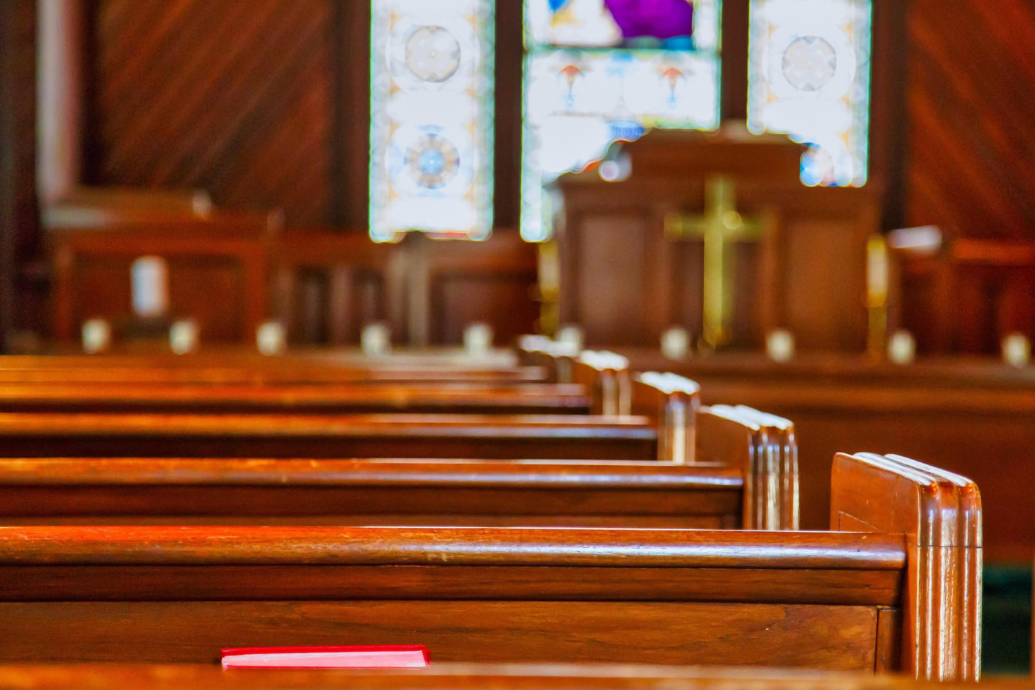 Empty church pews lit by stained glass windows