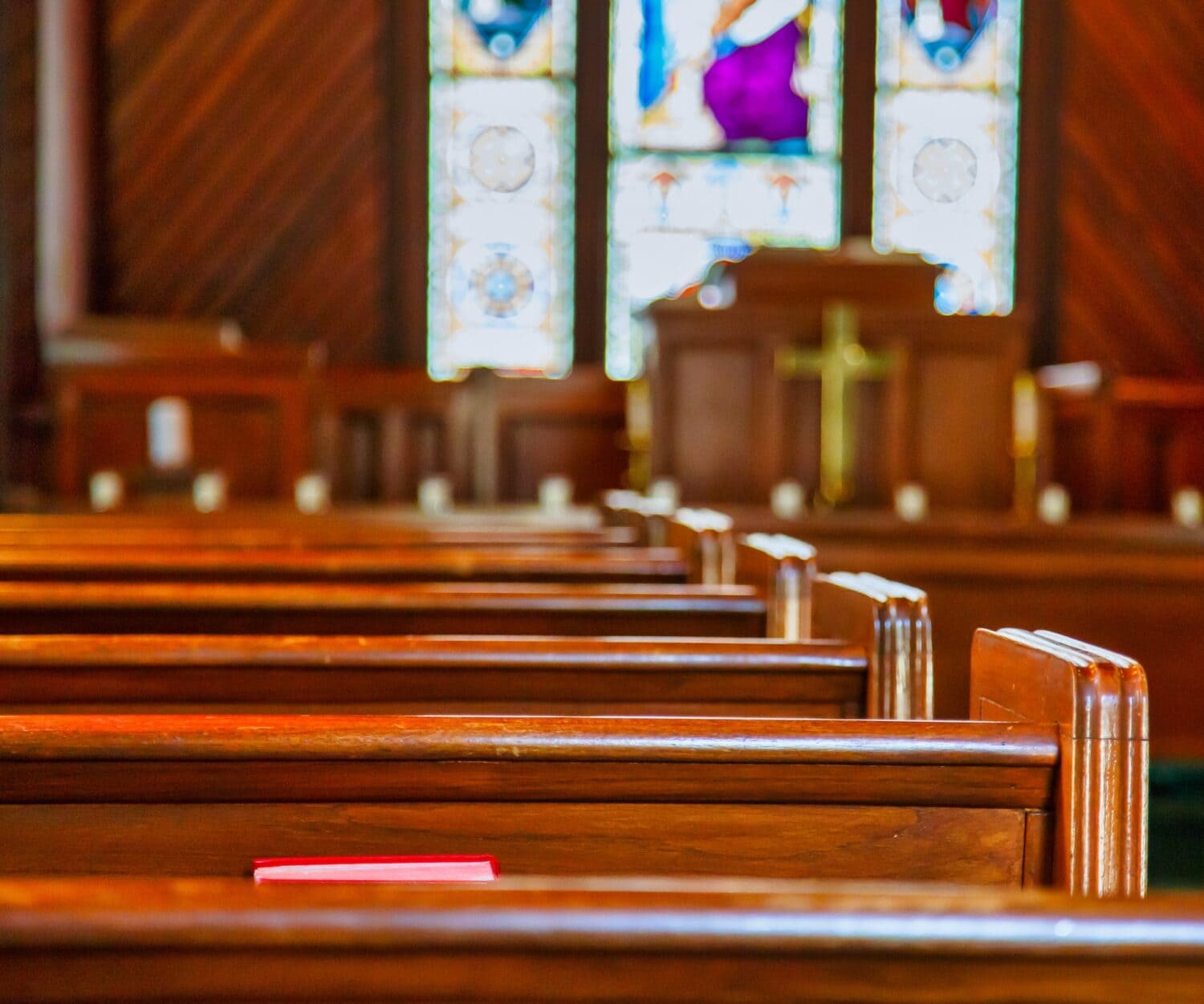 Empty church pews lit by stained glass windows