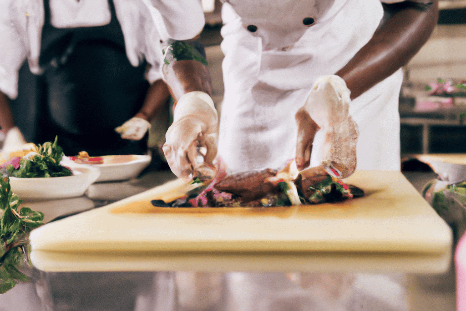 Chef plating a finished meal on a restaurant kitchen counter