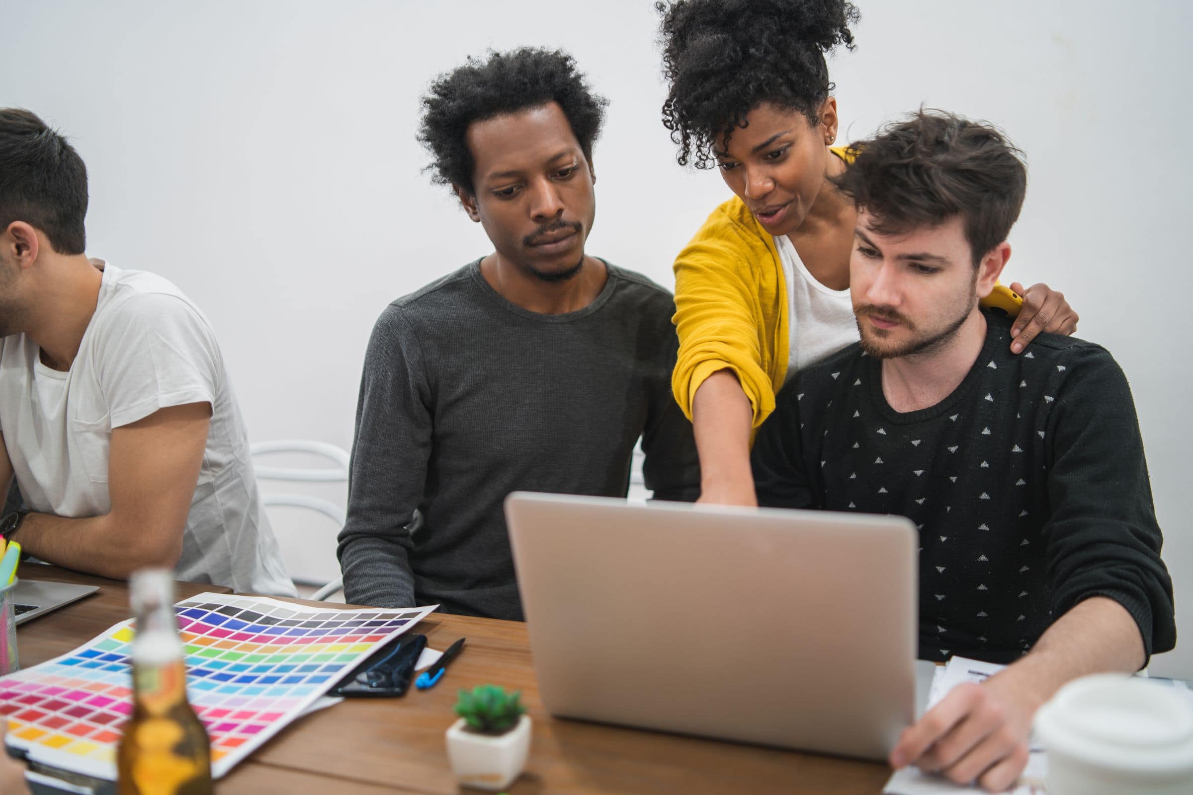 Web design team reviewing a project on a laptop with color swatches