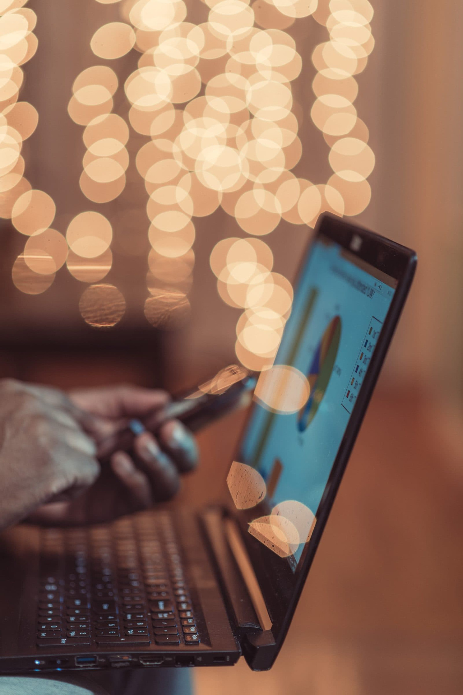 Laptop showing marketing data charts, lit by warm bokeh lights
