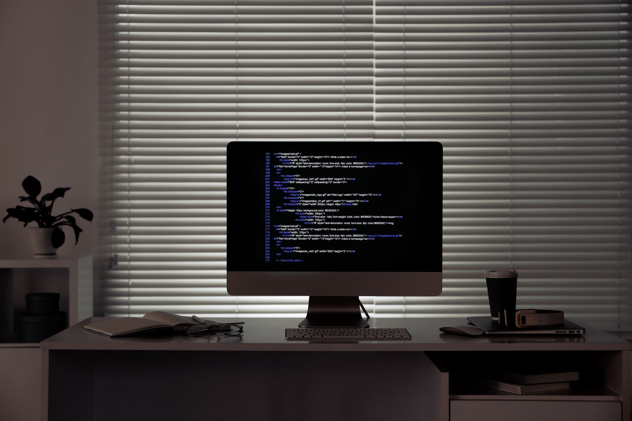 Computer monitor showing website code on a desk