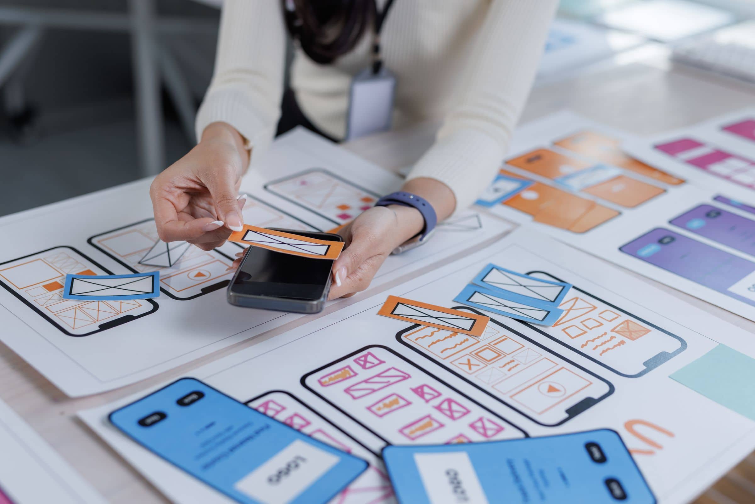 Designer arranging mobile app screen layouts on a table