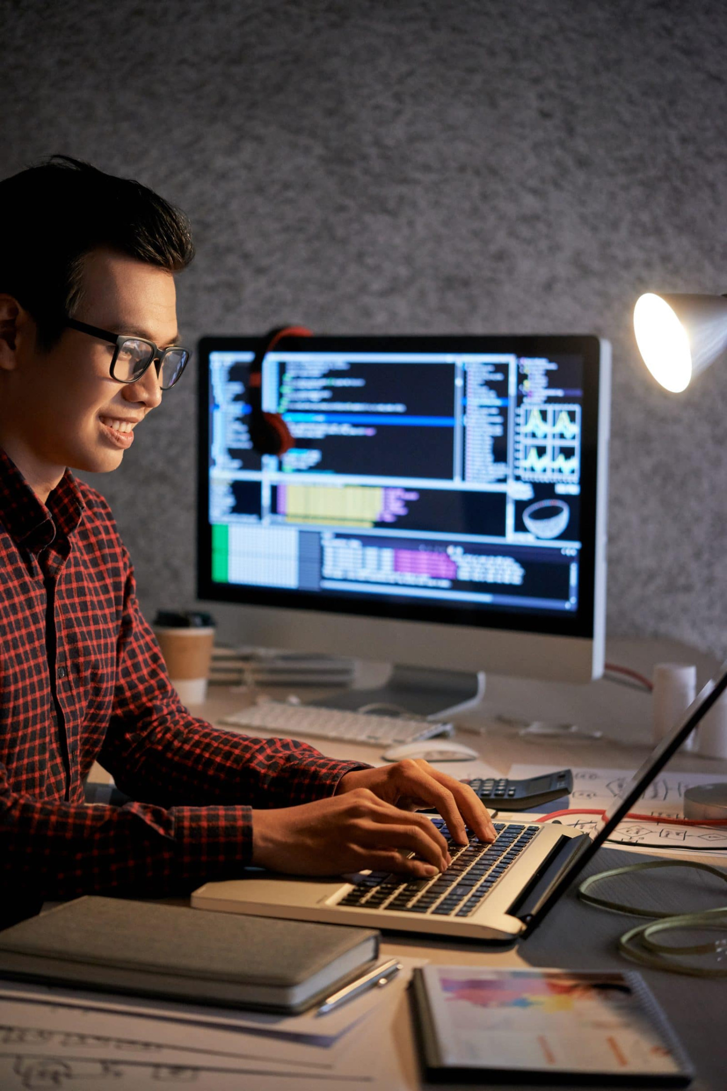 Web designer coding a website on a laptop at a desk at night